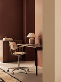 Audo Copenhagen Co Task Chair, Non-Upholstered, Co Task Chair in light oak veneer sits at a dark desk with a Torso Table Lamp in a warm, brown-toned office setting