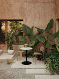 Audo Copenhagen Co Dining Chair, Outdoor, cozy outdoor setting with two olive Co Dining Chairs, Harbour Column Table, and Ray Table Lamp, surrounded by lush plants