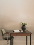 Audo Copenhagen Co Task Chair, Fully Upholstered, With Arms, Co Task Chair, Fully Upholstered in green, at a wood desk with a book, a glass of water, and a vase of white tulips