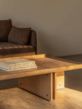 Audo Copenhagen Conrad Lounge Table, natural oak Conrad Lounge Table with curved edges and exposed screws, styled next to a textured brown Offset Sofa