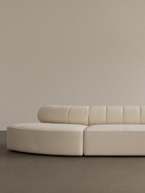 Audo Copenhagen Eave Seamline Modular Sofa, Rounded Modules, 34" Depth, close-up of the Eave Seamline Modular Sofa in cream bouclé, with its curved form and detailed backrest stitching