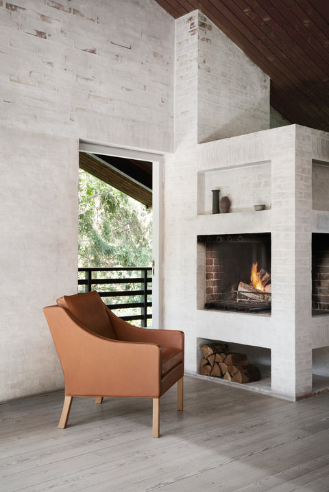 Borge Mogensen 2207 leather lounge chair by Fredericia beside a wood burning fireplace in a Scandinavian home