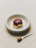 HAY Barro Bowls, Off-White, glazed terracotta serving bowl, holding a set custard with berry sauce beside a spoon on cream linen