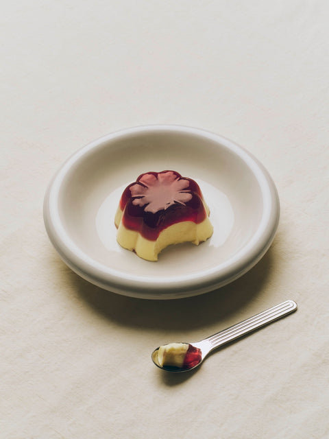 HAY Barro Bowls, Off-White, glazed terracotta serving bowl, holding a set custard with berry sauce beside a spoon on cream linen