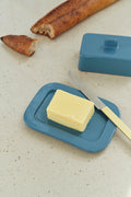 HAY Barro Butter Dish, Dark Blue, glazed terracotta butter dish, open with a block of butter, a yellow handled knife and bread nearby