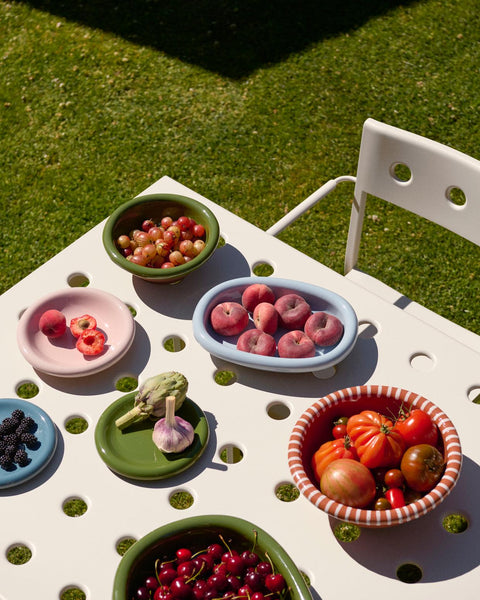 HAY Barro Oval Dish, Small, Green, glazed ceramic oval serving dish, bowls and dishes of fruit on a white outdoor table on a sunlit lawn