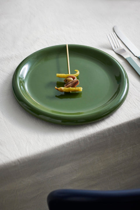 HAY Barro Plates, Green, glazed portuguese terracotta plates, one plate with a small skewer of appetizers on a white tablecloth with a fork