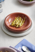 HAY Barro Bowls, Natural, glazed terracotta serving bowl, holding beans on a white plate with a blue napkin and cutlery