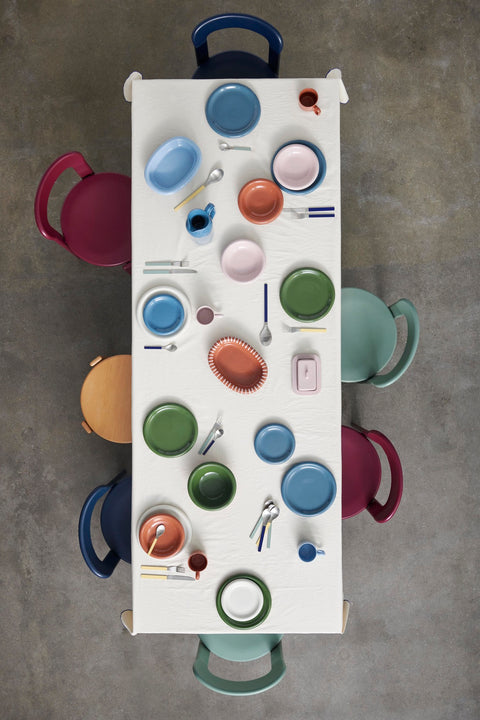 HAY Barro Plates, Green, glazed portuguese terracotta plates, overhead of a long white table laid with colourful plates, oval dishes and mugs