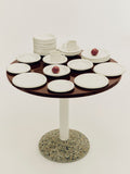HAY Barro Bowls, Off-White, glazed terracotta tableware, filling a round dark red table with a terrazzo base and cream tube