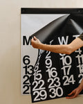 Detail view of a black monthly page being peeled from the 2026 Stendig Calendar