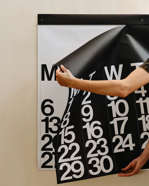 Detail view of a black monthly page being peeled from the 2026 Stendig Calendar