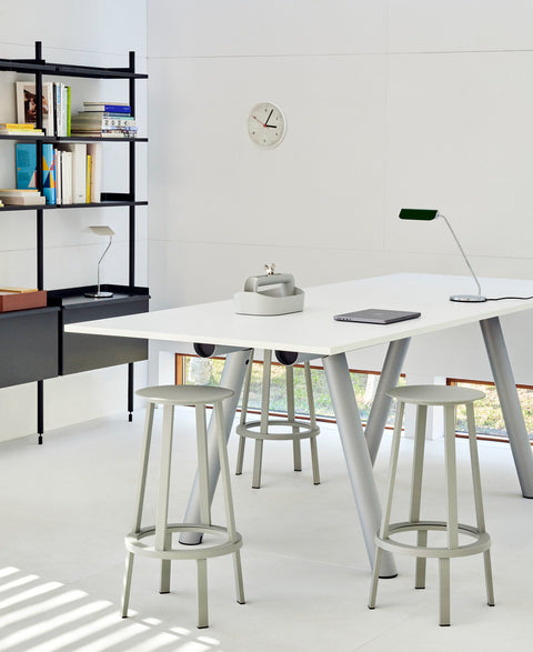 HAY Wall Clock, White, recycled ABS wall clock, mounted above black shelving in a bright room with a white high table and grey stools