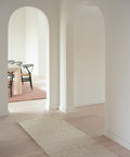 white boucle runner in hallway with oak floors and white walls