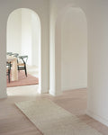 white boucle runner in hallway with oak floors and white walls