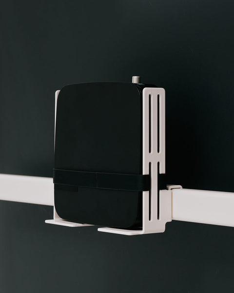 Pedestal Box Mount in Pearl, adjustable media device mount, holding a media box behind a screen