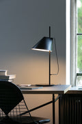 scandinavian table lamp with black finish on a desk, lamp designed by louis poulsen