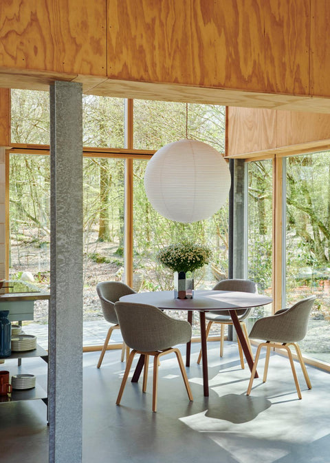 HAY Arcs Vase, Large, Mirror, mirror finish steel vase, holding white daisies on a round dining table with grey chairs under a paper lantern