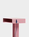 Pedestal Cable Clips in Ultra Marine, magnetic silicone cable clip, holding a cable against the edge of a pink desk