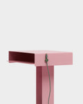 Pedestal Cable Clips in Mossy Green, magnetic silicone cable clip, holding a cable against the edge of a pink desk
