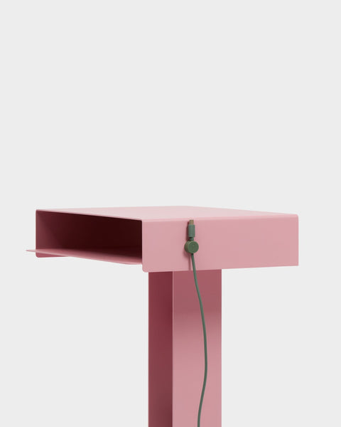 Pedestal Cable Clips in Mossy Green, magnetic silicone cable clip, holding a cable against the edge of a pink desk
