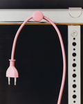 Pedestal Cable Dots in Bubble Gum, magnetic silicone cable holder, holding a pink power cable against a dark panel