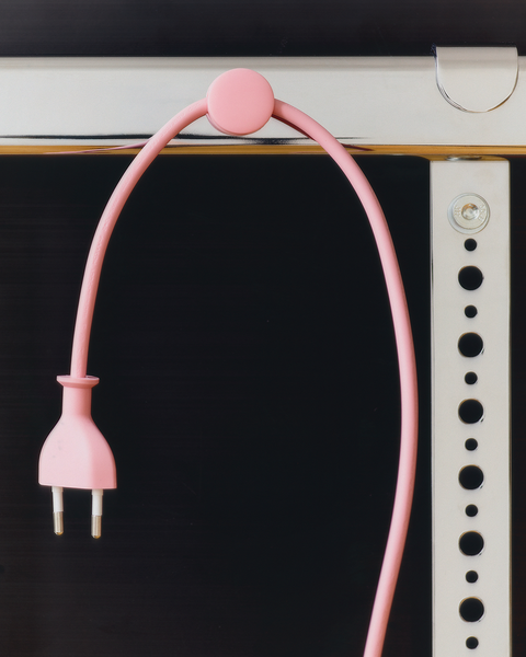 Pedestal Cable Dots in Bubble Gum, magnetic silicone cable holder, holding a pink power cable against a dark panel