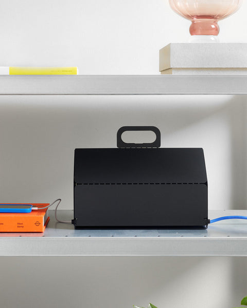 Pedestal Cable House in Charcoal, closed steel cable box on a shelf with a cable running out of the side