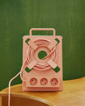 Pedestal Cable Stand in Dusty Rose, holding a coiled cable and power bar on a wooden table against a green wall
