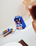 Pedestal Cable Stand in Ultra Marine, standing on a white surface with a coiled cable, books and a vase alongside