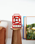 Pedestal Cable Stand in Fire Red, holding a coiled cable on a wooden stool beside a leather sofa and framed prints