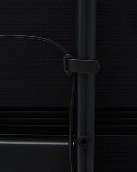 Pedestal Cable Tie in Charcoal, soft silicone cable tie, holding a cable against the leg of a Charcoal TV stand