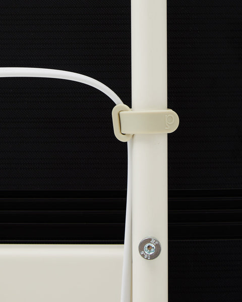 Pedestal Cable Tie in Pearl, soft silicone cable tie, holding a cable against the leg of a Pearl TV stand