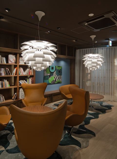 Louis Poulsen PH Artichoke pendant in white illuminating a cozy library lounge with Egg chairs and built in bookcase