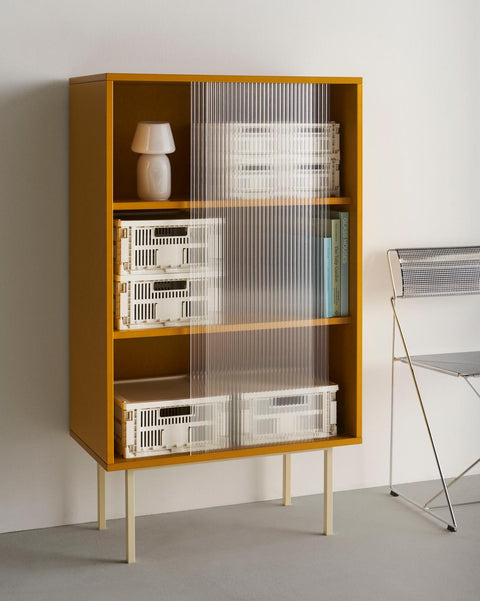 HAY Colour Crate, Medium, Off-White, recycled plastic storage crates, stacked with lids inside a yellow cabinet with fluted glass doors