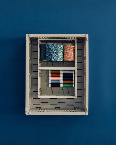 HAY Colour Crate, Mini, Grey, recycled plastic storage crate, grey crates seen from above holding rolled textiles and pencils on deep blue