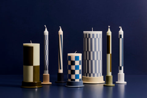 HAY Column Candleholder, Off-White, glazed ceramic candleholders, a row holding block and check candles on a dark blue surface