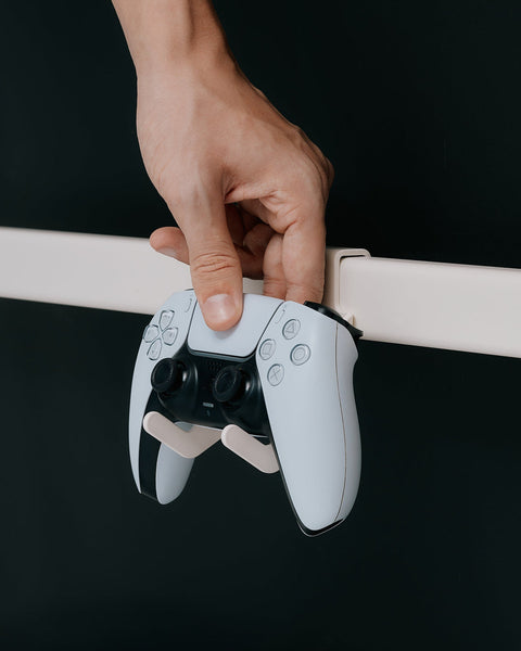 Pedestal Controller Mount in Pearl, a hand setting a white game controller into the holster on a stand bar