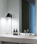 black minimal wall lamp in a bathroom by louis poulsen 