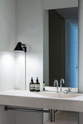 black minimal wall lamp in a bathroom by louis poulsen 