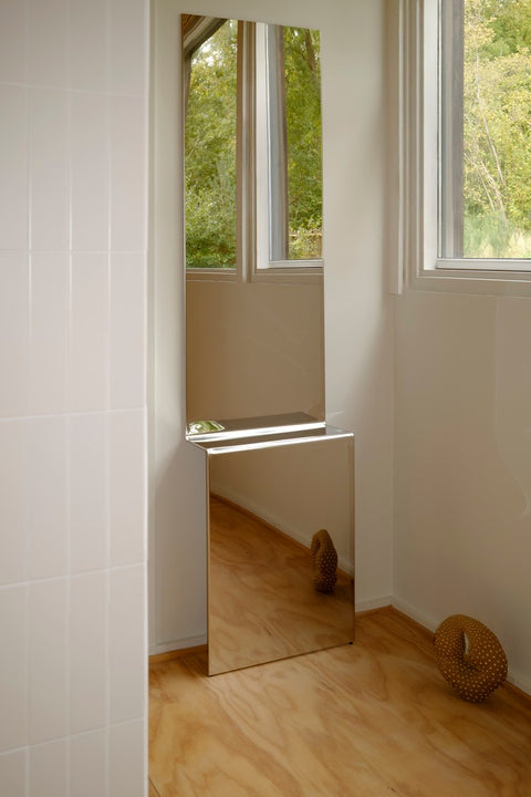 Pleat Mirror by Muuto in polished stainless steel full length mirror reflecting window light in minimalist space