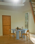 Muuto Re Norm Table 130 in light blue with oak chairs and Beam portable lamp in dining setting