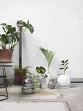 Minimalist interior featuring Muuto's Silent Vase in Glass, placed on a wooden table with soft lighting.