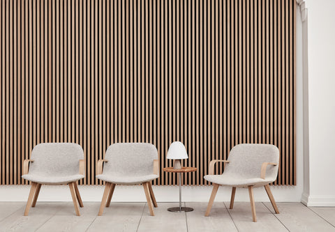 Three Fredericia Eyes Lounge Chairs in light grey with oak arms and legs beside a small table and lamp, slatted wood wall backdrop