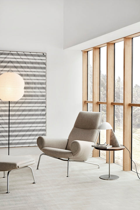 Hans J. Wegner Queen Chair by Fredericia in light wool with brushed steel base beside window with Pal side table and Fellow lamp