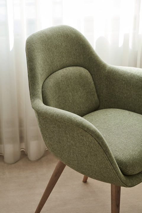 Detail of Swoon Dining Chair with oak wood base in green fabric upholstery by Fredericia.