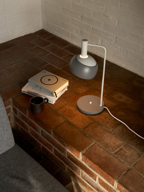 Finn Juhl FJ Elements grey table lamp by Louis Poulsen beside books and mug, adjustable modern Scandinavian lamp.