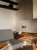 Finn Juhl FJ Elements grey table lamp by Louis Poulsen lighting a brick ledge living room, cozy Scandinavian design.