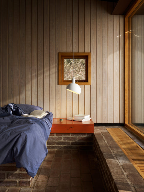 Finn Juhl Elements pendant lamp in white by Louis Poulsen used as bedside pendant in Scandinavian bedroom with wood panel wall Canada