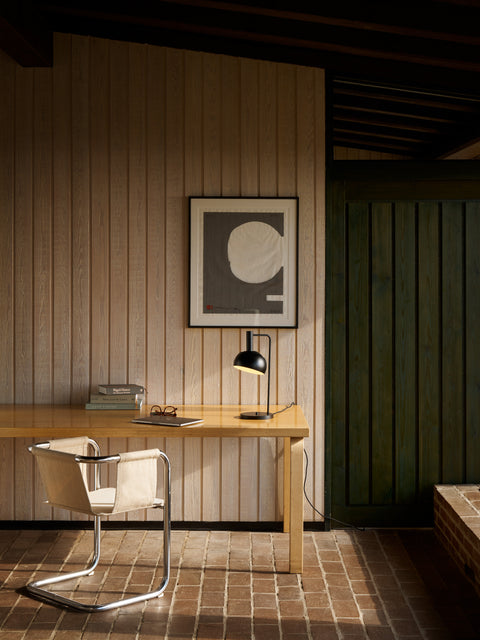 Finn Juhl FJ Elements black table lamp by Louis Poulsen on minimalist desk with chair, modern home office lighting.